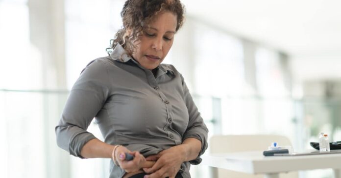 Image of a women injecting a medication pen into her stomach