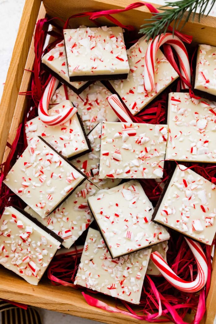 Square peppermint bark pieces stacked on top of each other in a gift box.