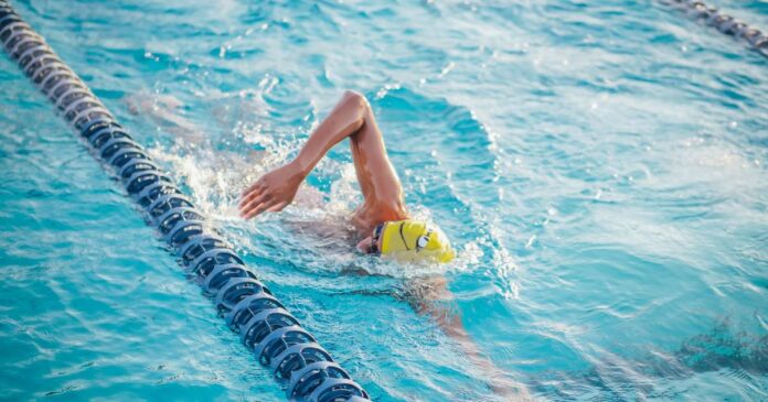 Person doing freestyle stroke in a swimming pool lane