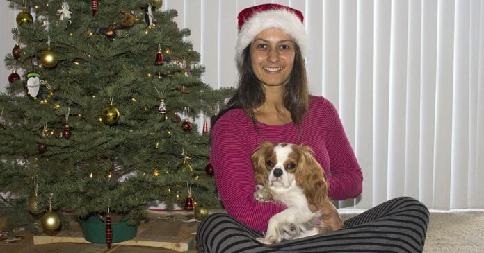 Christel sitting with dog in front of Christmas tree