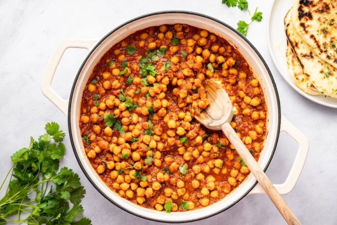 chana-masala-hero-horizontal.jpg Thick and flavorful chana masala simmering on the stovetop with a wooden spoon.